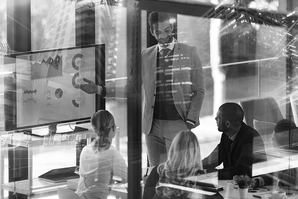 Executive team reviewing AI strategy options in a glass-walled boardroom