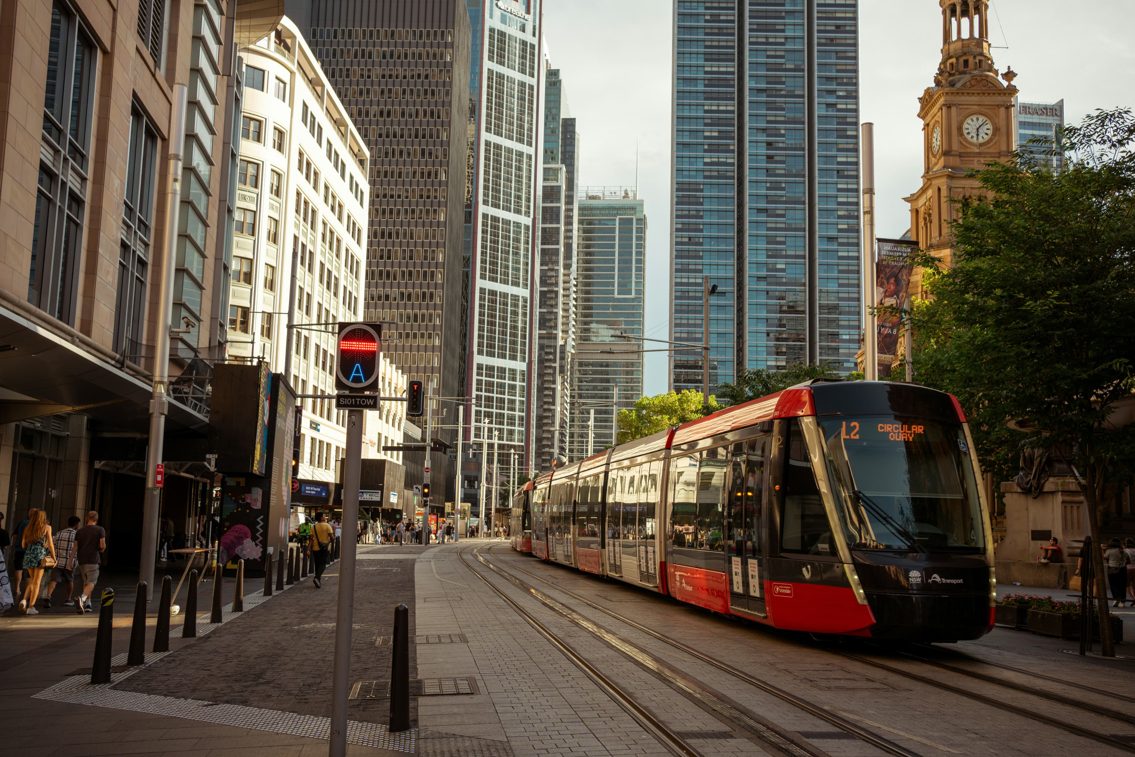 Sydney CBD street scene with a light rail tram on George Street and the QVB clock tower
